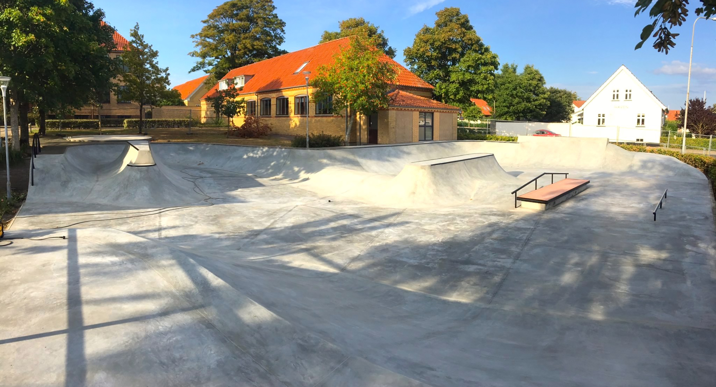 Et overbliksbillede af en skatepark i beton foran en gul bygning