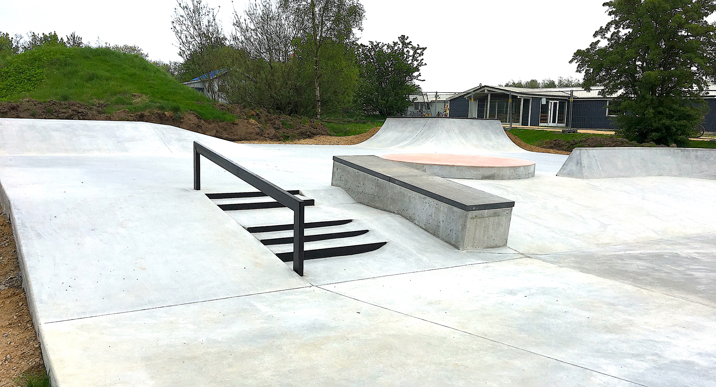 En skatepark med rail, dobbeltsæt trappe og ledge i beton