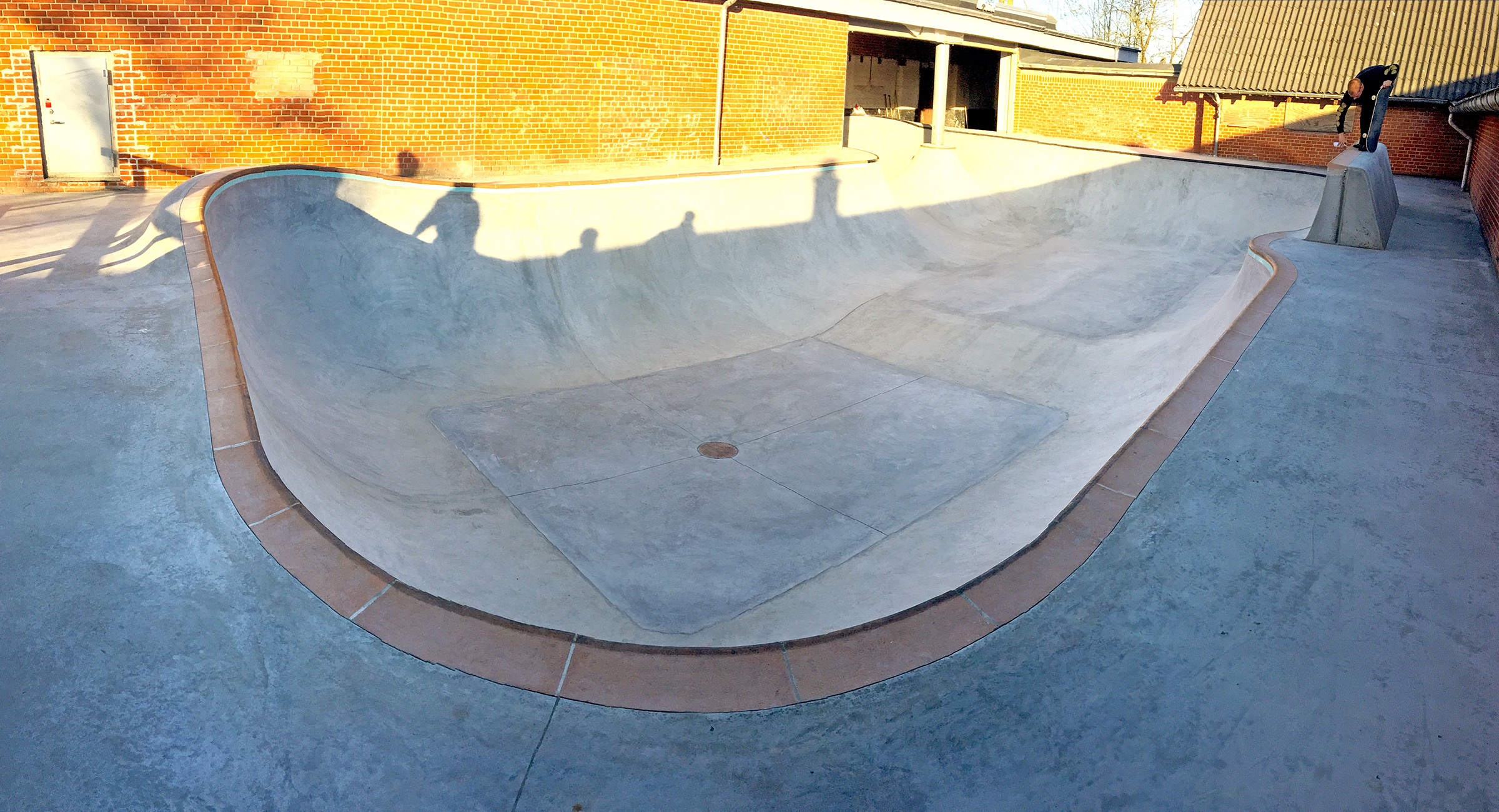 En skater står på en stor extension midt i en betonbowl