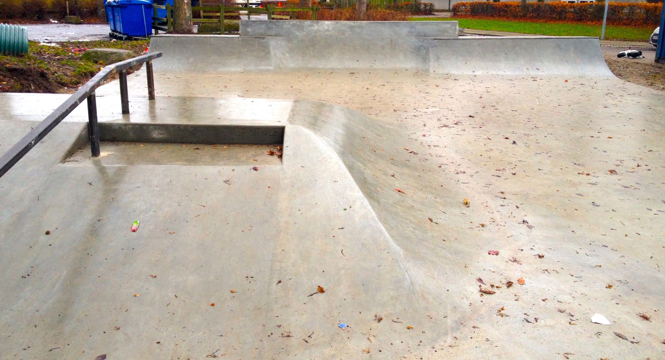 Her ses en skateboardrampe i beton med et metalgelænder på toppen