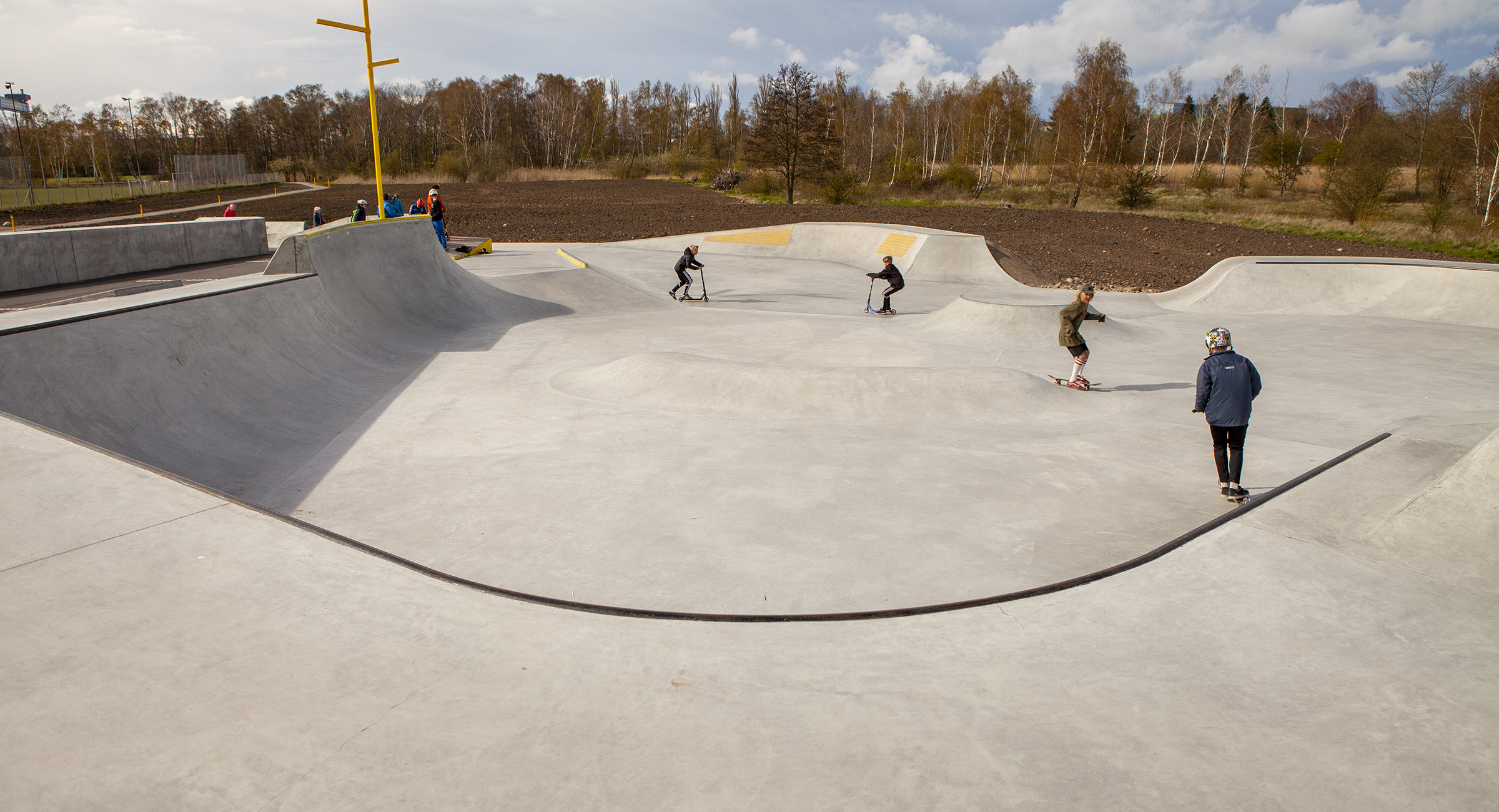 Skatere kører i bunden af en stor betonrampe i Munkebo Bypark