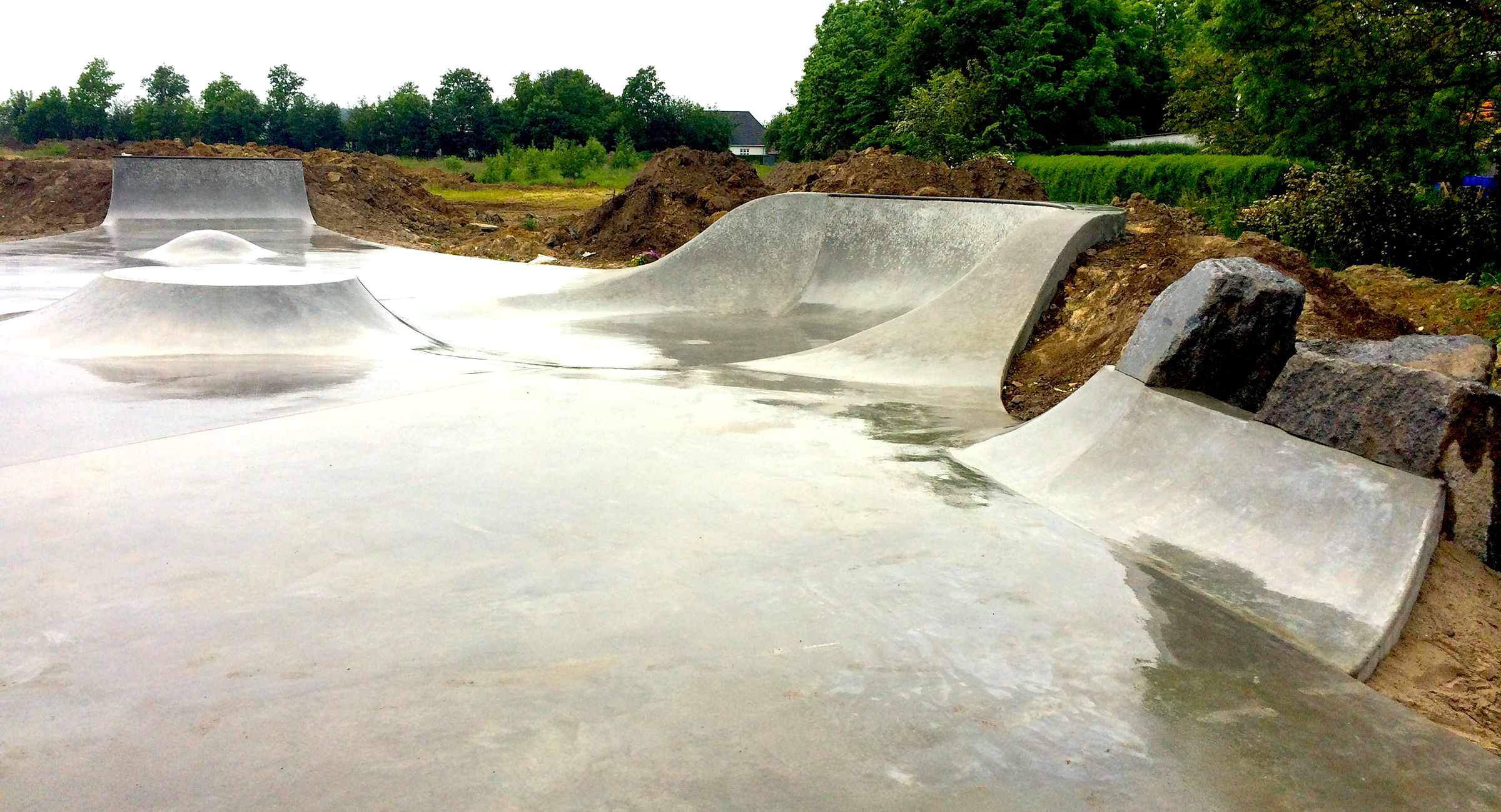 Billedet viser en beton skatepark i regnvejr