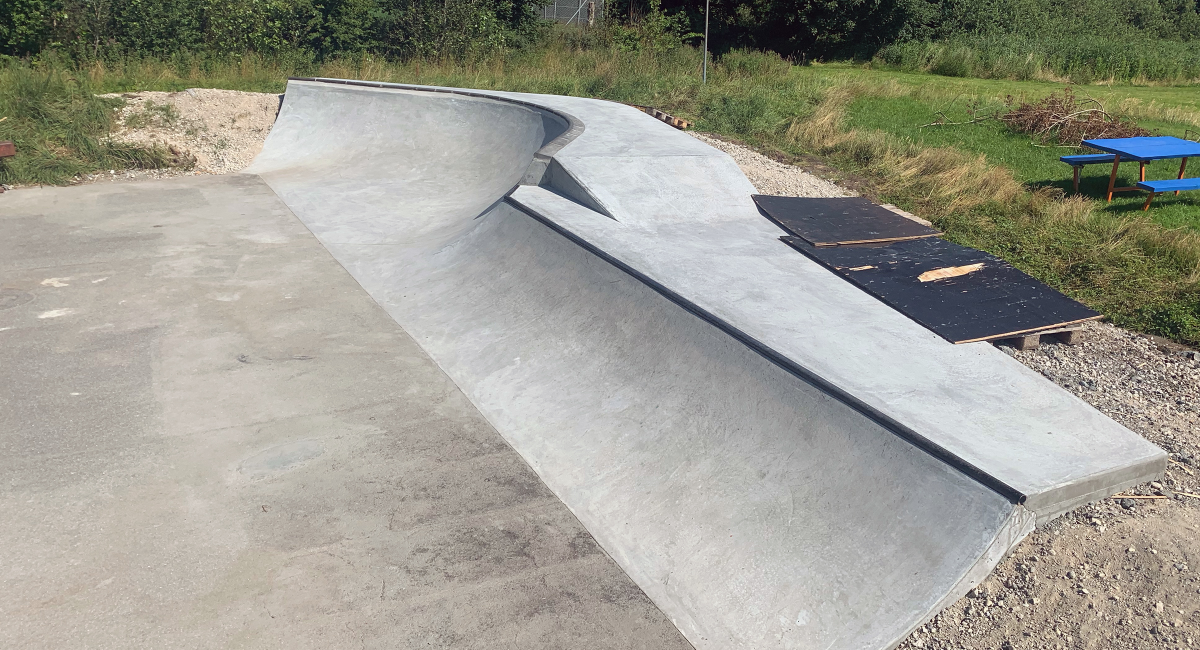 Her ses en buet skateboardrampe i beton. Den ene halvdel har en ret vinkel, mens den anden halvdel buer indad