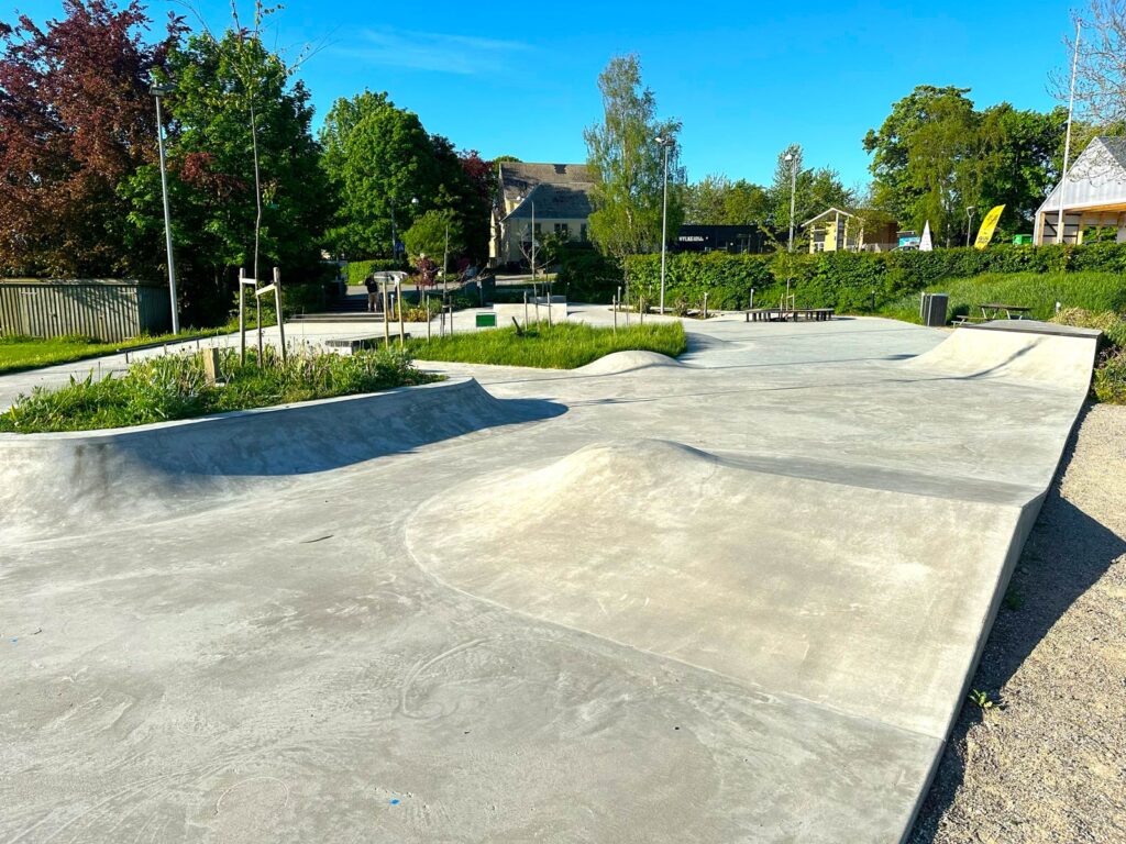 Beton skatepark i Hylke Bypark med små hips og en stor plantekumme med transitioner opad