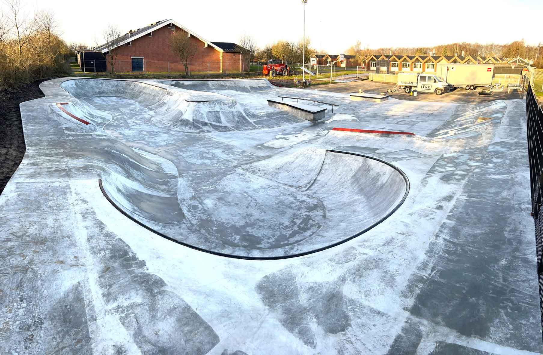 En transition i beton støbt på stedet i hjørnet af en stor skatepark i Vester Hassing