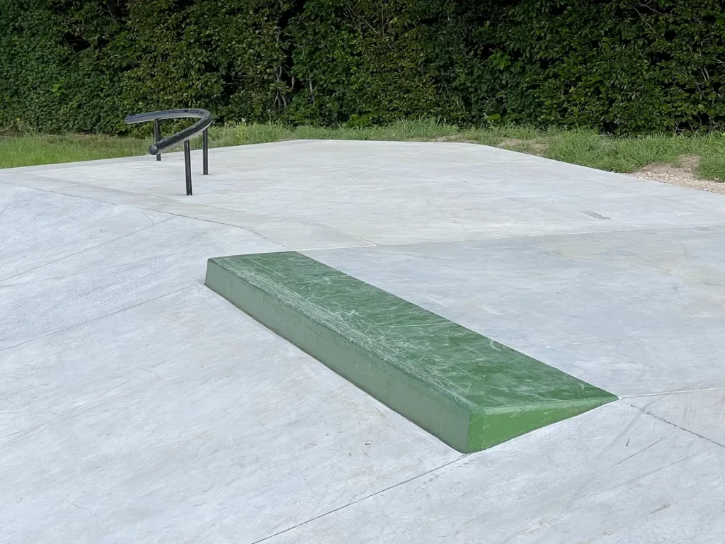 Nærbillede af grøn slappykant på toppen af en bank i beton. Bagved set et sort buet rail.