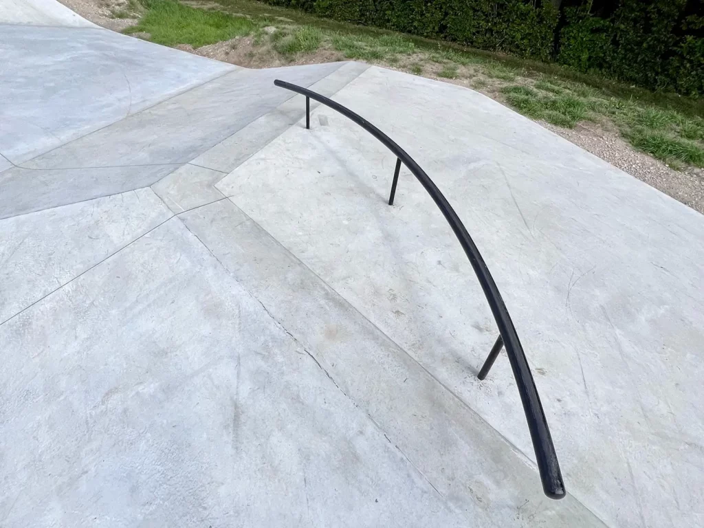 Buet sort rail i metal på toppen af en betonhip i Svinninge Skatepark