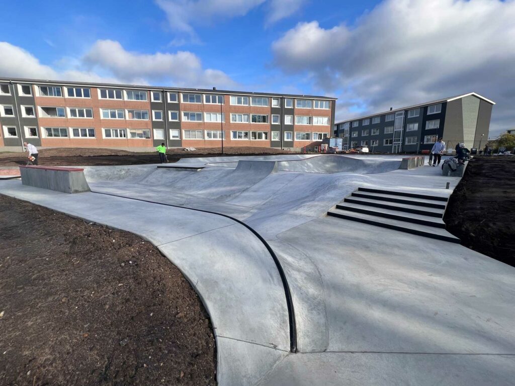 Nybygget skatepark i beton foran boligblokke i Holstebro. Der ses både trapper og transitioner.