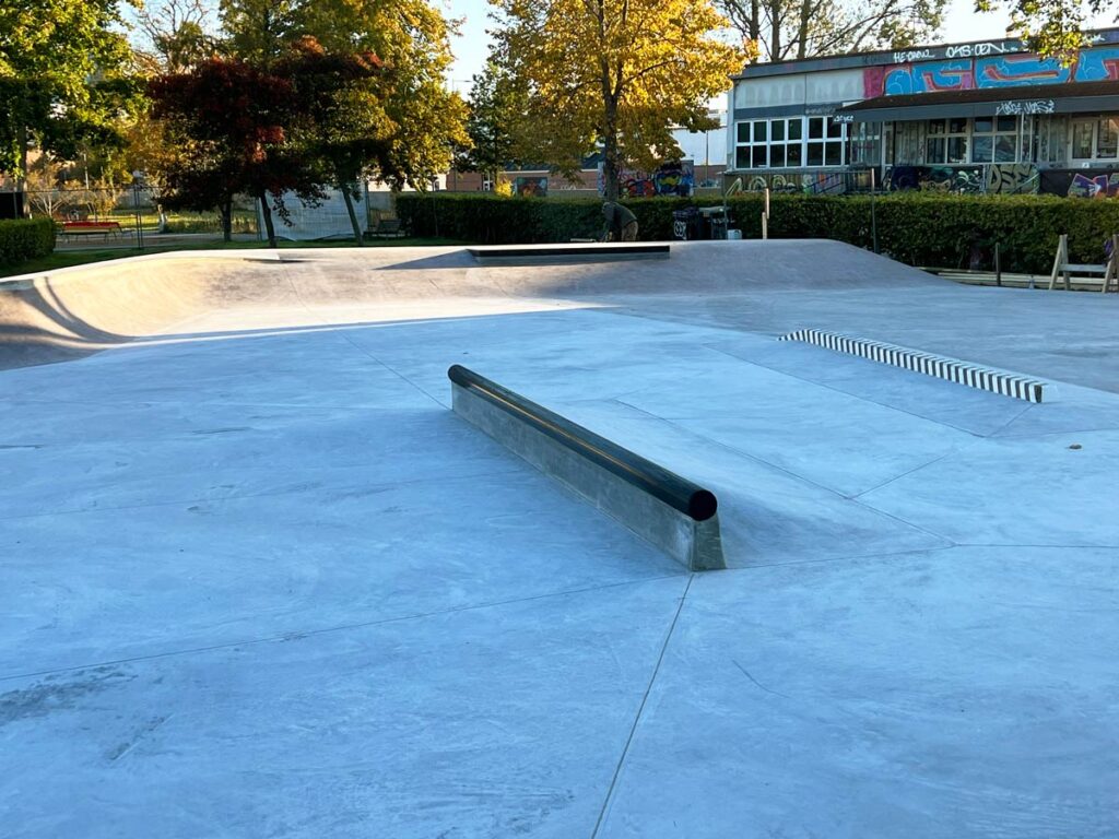 Et stort rør og en stribet slappy curb i Karolinelund skatepark som er støbt i beton