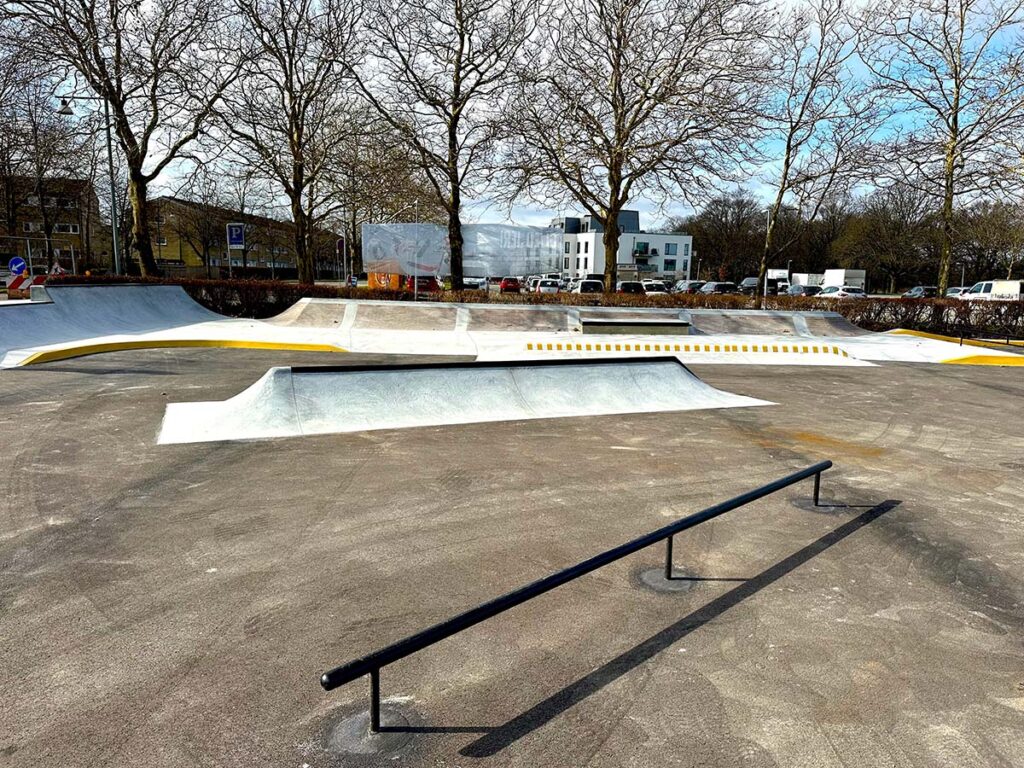 Et sort rail adskiller Glostrup Skatepark fra den street basket bane der støder op til