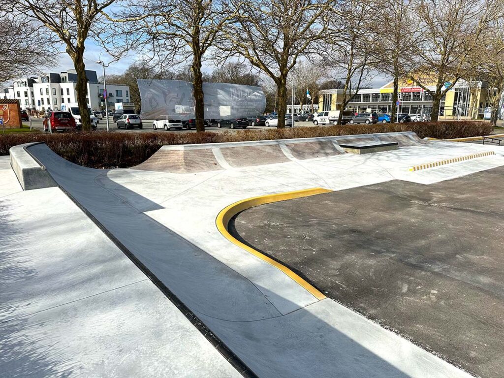 Beton quarterpipes med metalcoping og indmurede røde sten pynter i Glostrup Skatepark