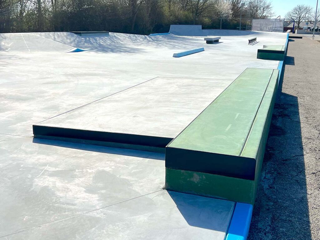 En grøn curb op ad en grå manual pad i Middelfart Skatepark på Middelfart Marina